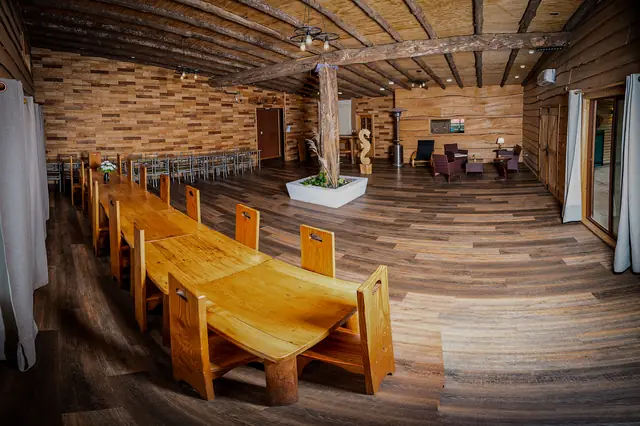 Salón de eventos montado con mesas y bancas largas de madera en Cabañas Kompatzki, Ancud