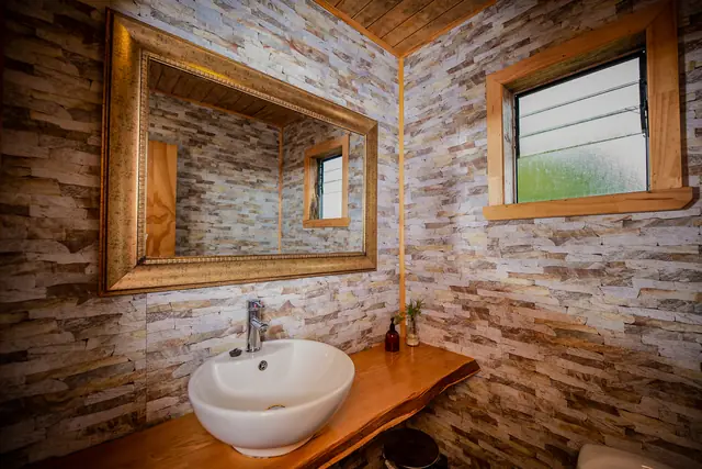 Baño del salón de eventos con lavamanos sobre mesón de madera