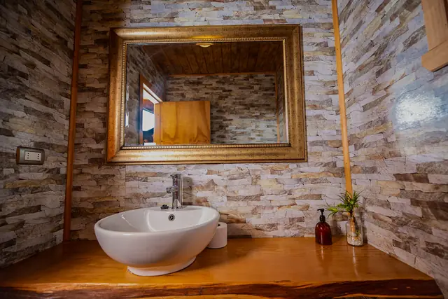 Baño del salón de eventos con espejo enmarcado en madera
