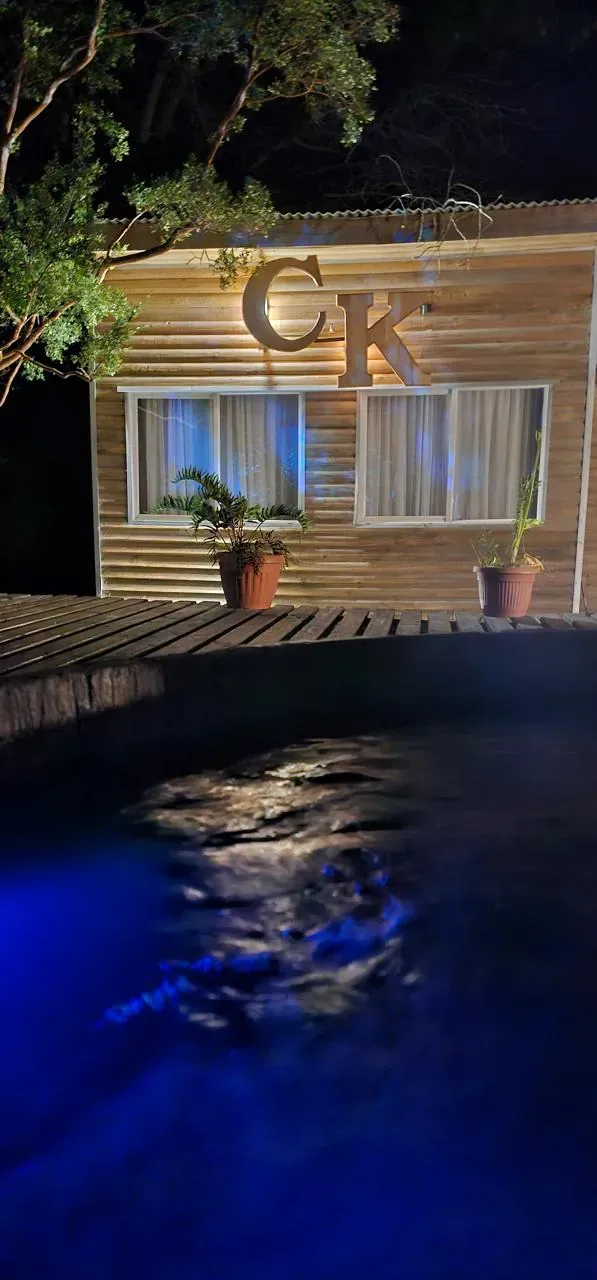 Tinaja con hidromasaje iluminada en azul de noche, bajo el letrero CK