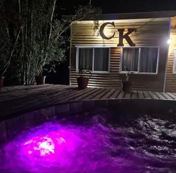 Tinaja con hidromasaje iluminada en fucsia de noche, en Cabañas Kompatzki, Ancud