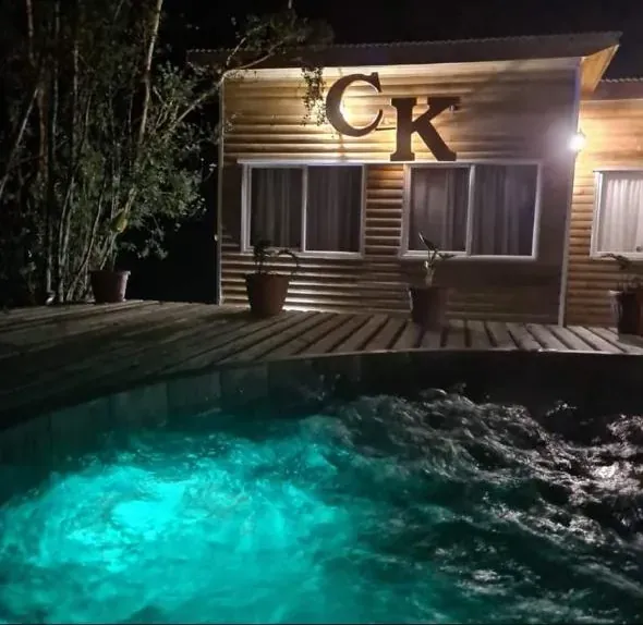 Tinaja con hidromasaje iluminada en turquesa de noche, frente al deck de Cabañas Kompatzki